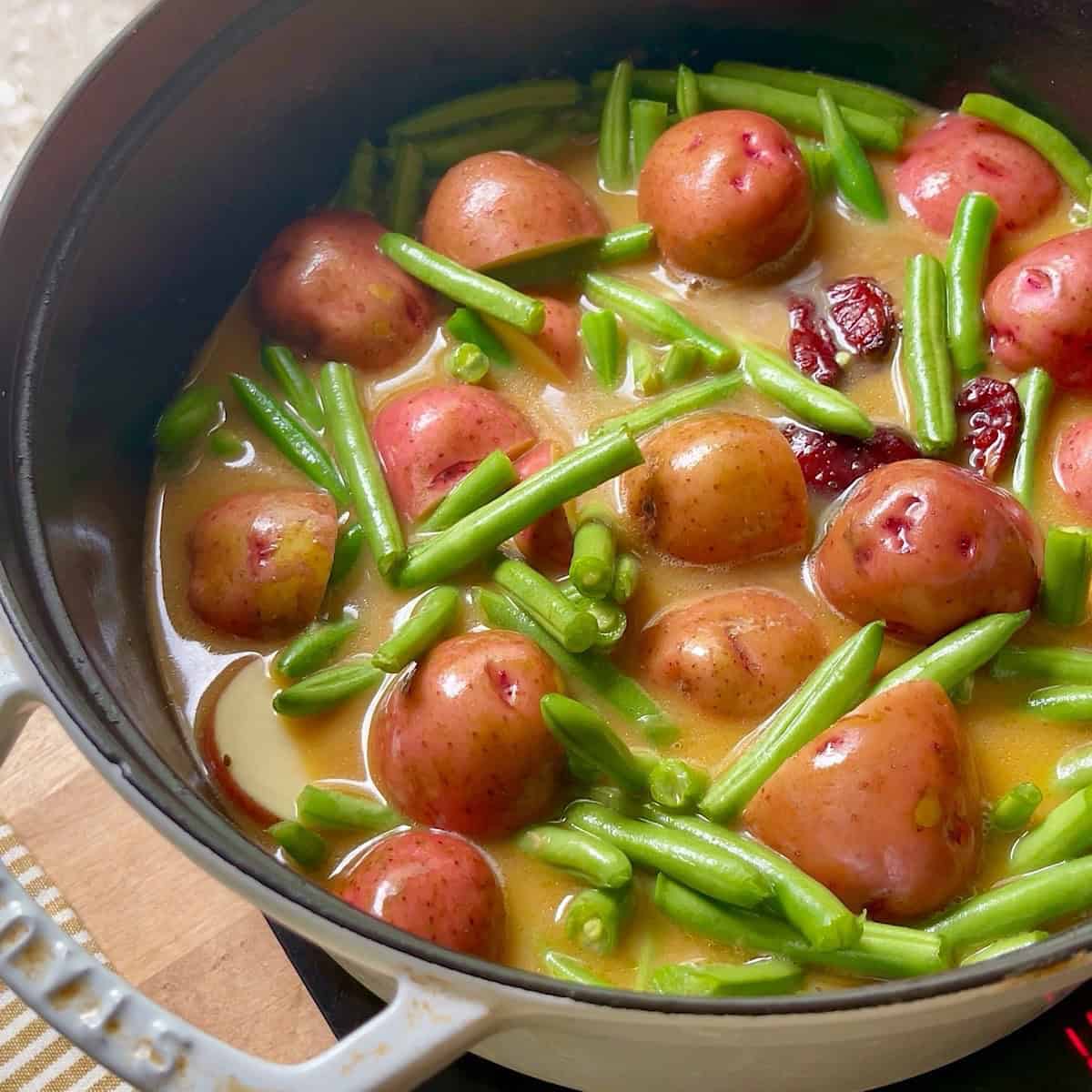 Trimmed green beans and halved new potatoes added to broth.