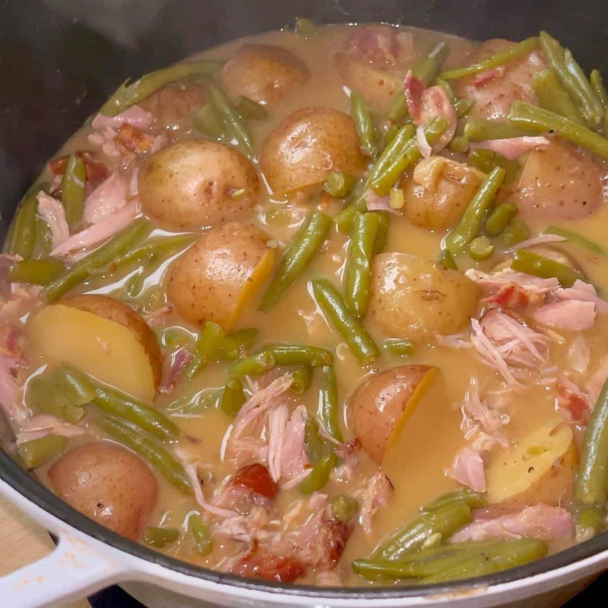 Southern green beans and potatoes with shredded turkey and bacon in a dutch oven.