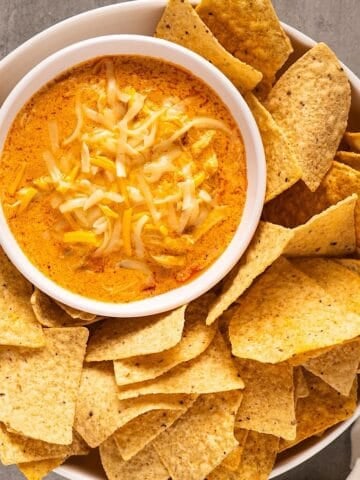 Buffalo chicken dip nestled in a serving dish surrounded by tortilla chips.