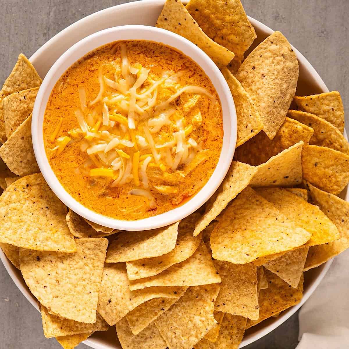 Buffalo chicken dip nestled in a serving dish surrounded by tortilla chips.