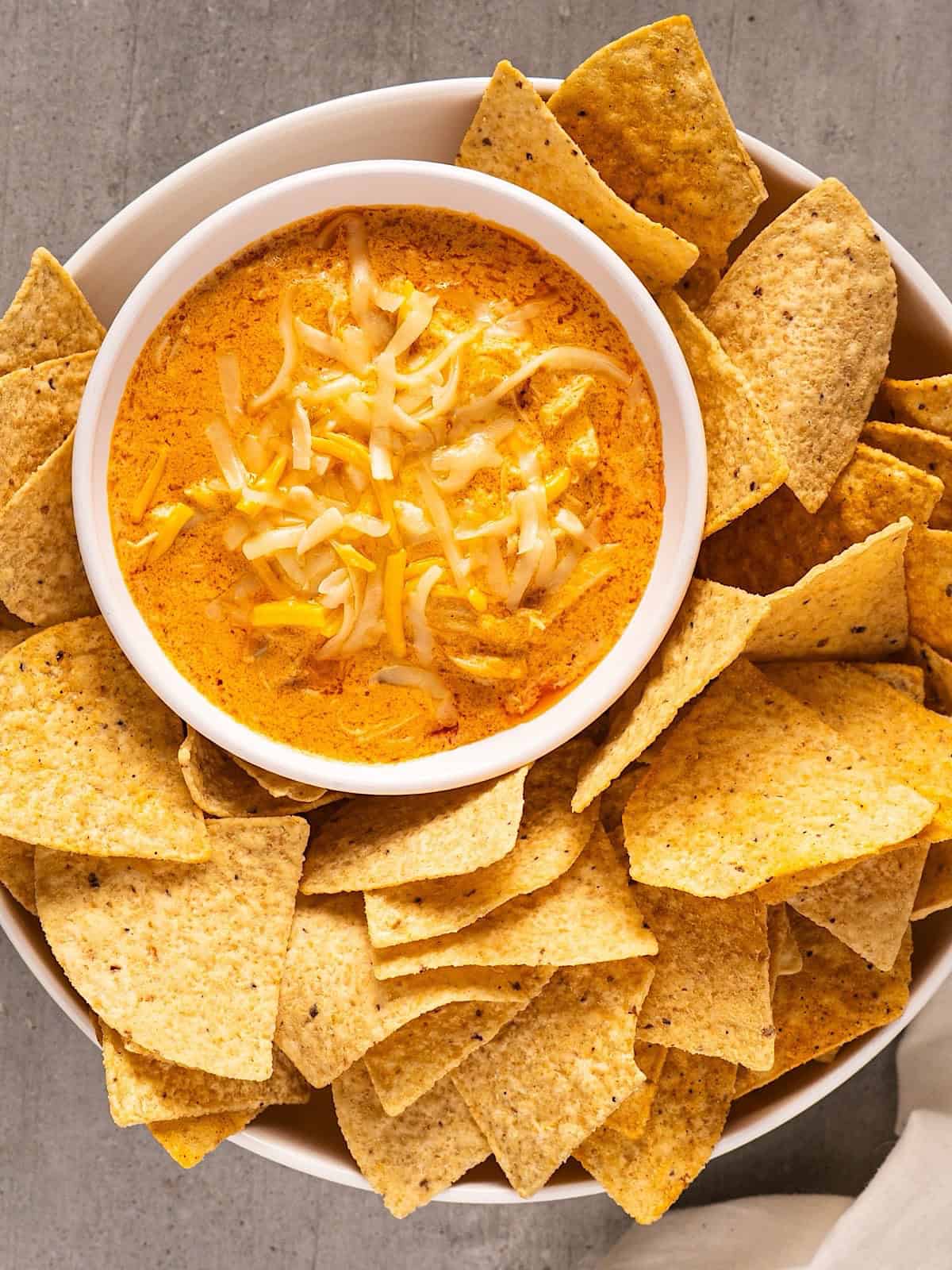 Buffalo chicken dip nestled in a serving dish surrounded by tortilla chips.