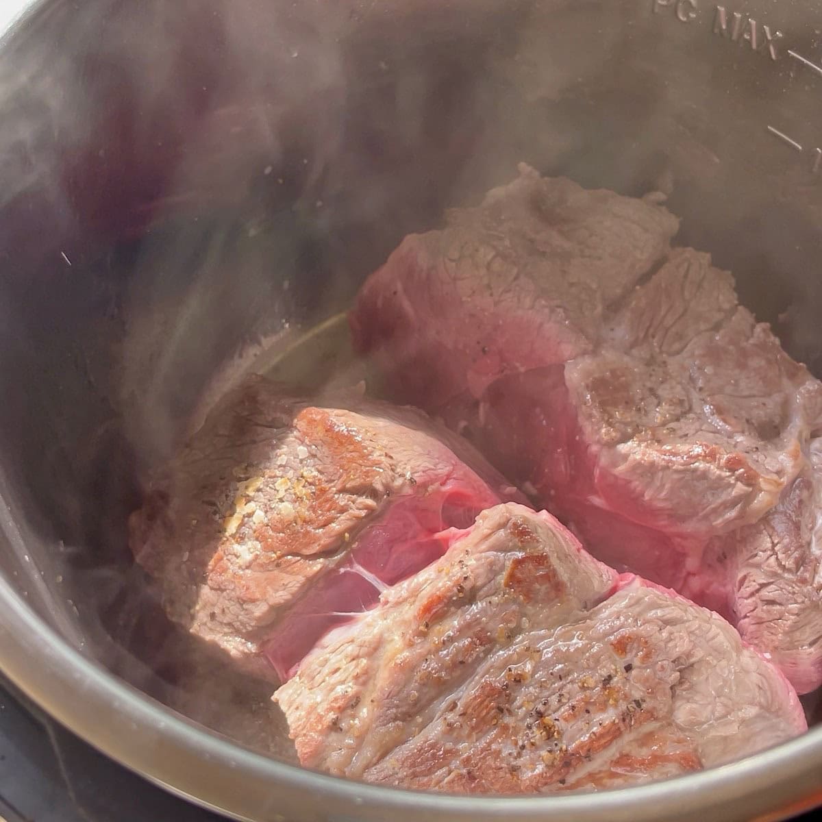 Seasoned chuck roast searing in the pressure cooker.