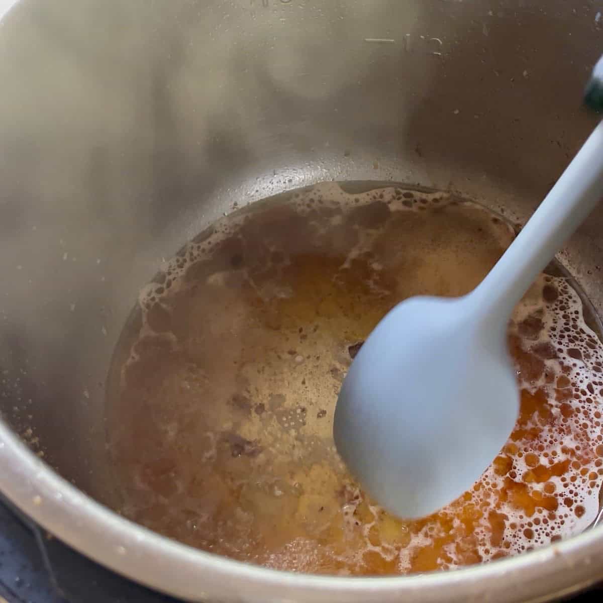 Deglazing and scraping brown bits with beef broth.