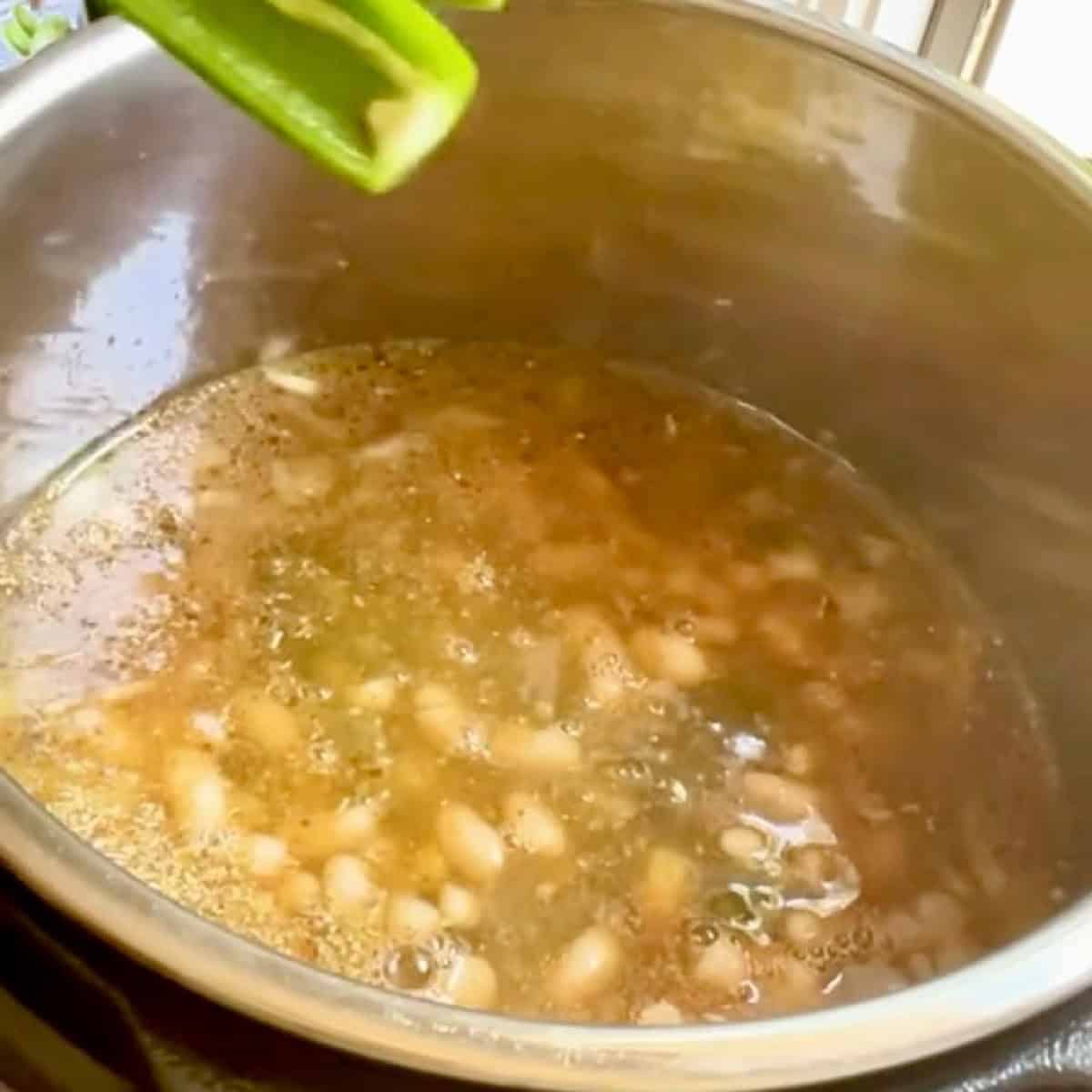 Adding white beans, jalapeno and chicken to the chicken chili broth.