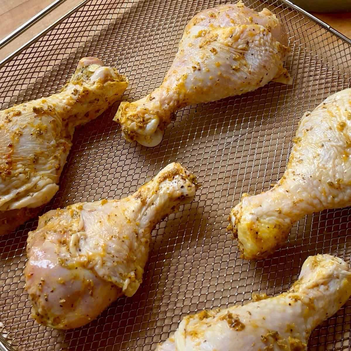 Lemon pepper chicken drumsticks lined up in air fryer basket.