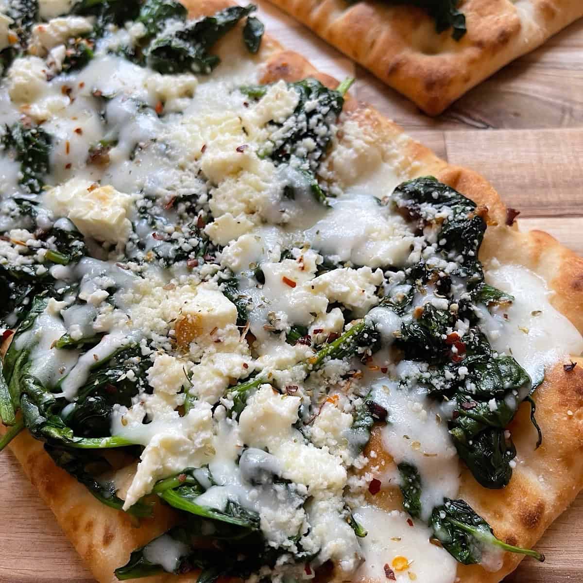 Baked spinach pizza with feta cheese removed from the oven.