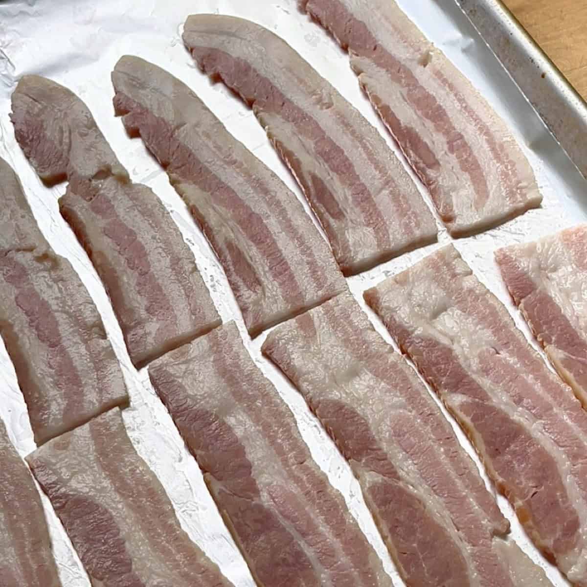 Bacon arranged on a sheet pan with foil ready to bake.