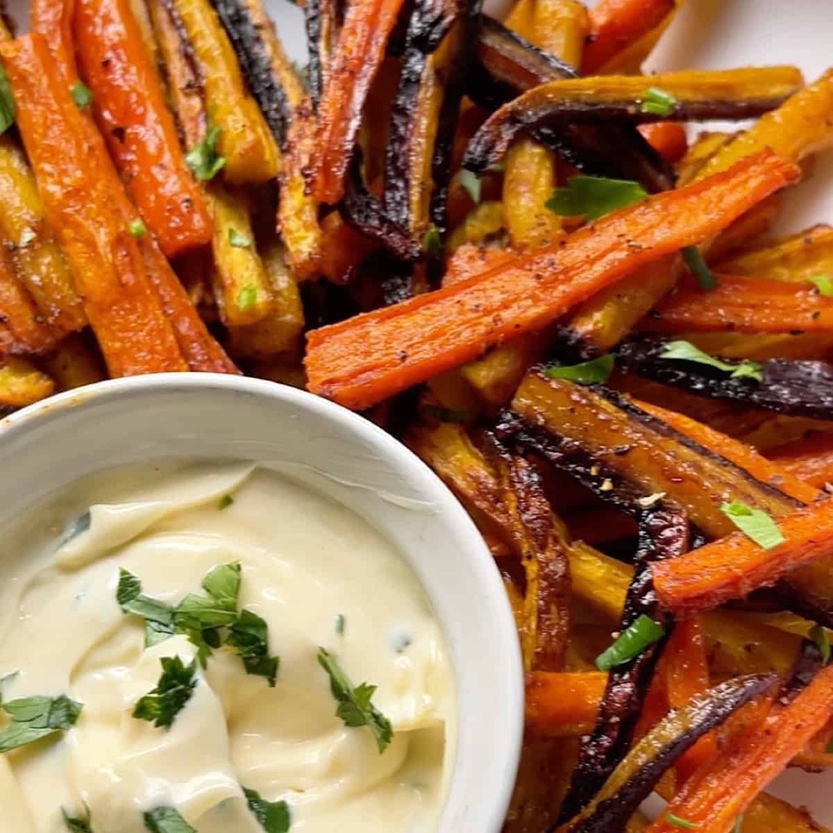 Baked carrot fries in a serving dish with dipping sauce.