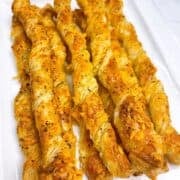 Cheese twists with puff pastry on a white serving platter.
