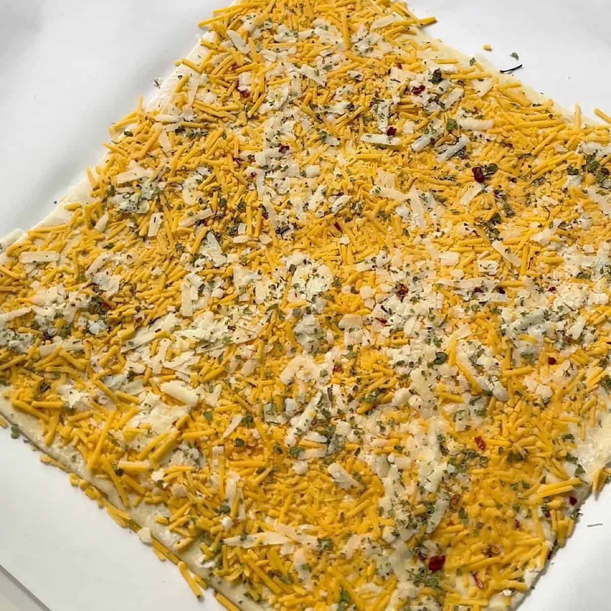 Cheeses and seasoning pressed into the dough.