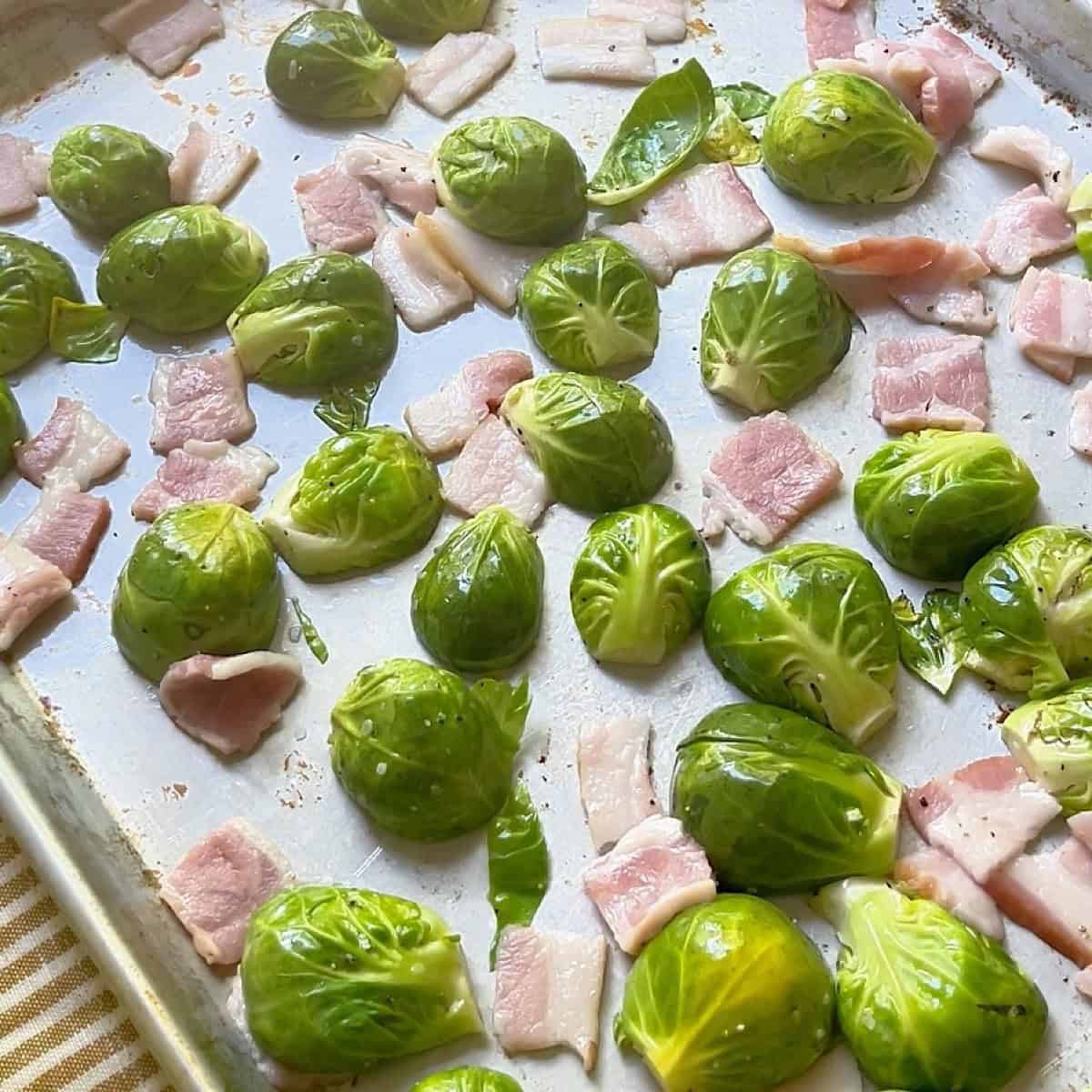 Brussels arranged face down on a sheet pan with bacon scattered throughout.