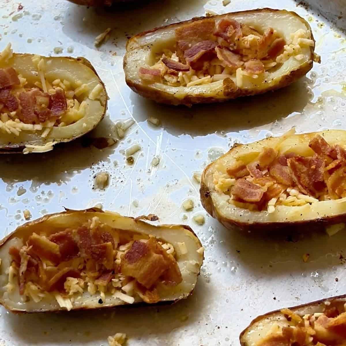 Baked potato halves with shredded cheese and bacon.