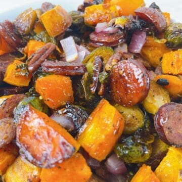 Fall sheet pan sausage, brussels sprouts, and sweet potatoes in a serving bowl.