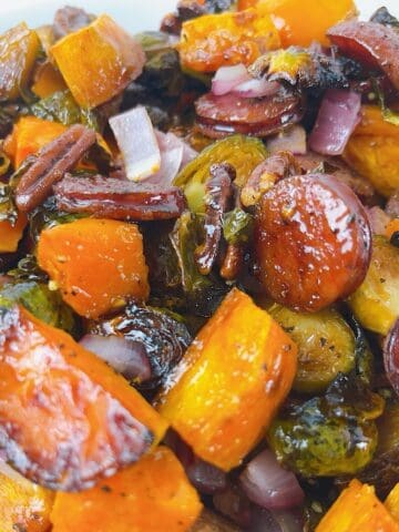 Fall sheet pan sausage, brussels sprouts, and sweet potatoes in a serving bowl.