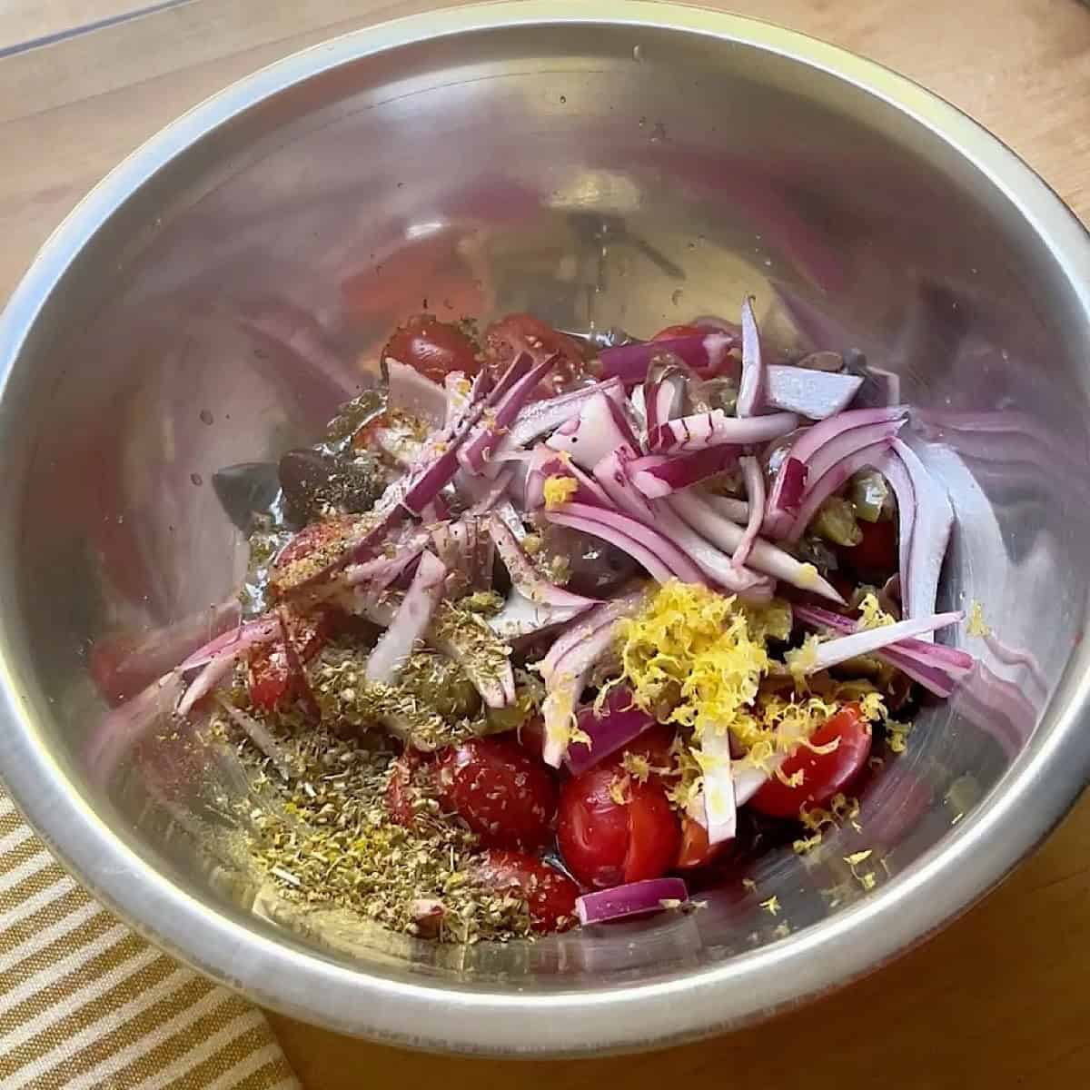 Combining Mediterranean toppings in a mixing bowl.