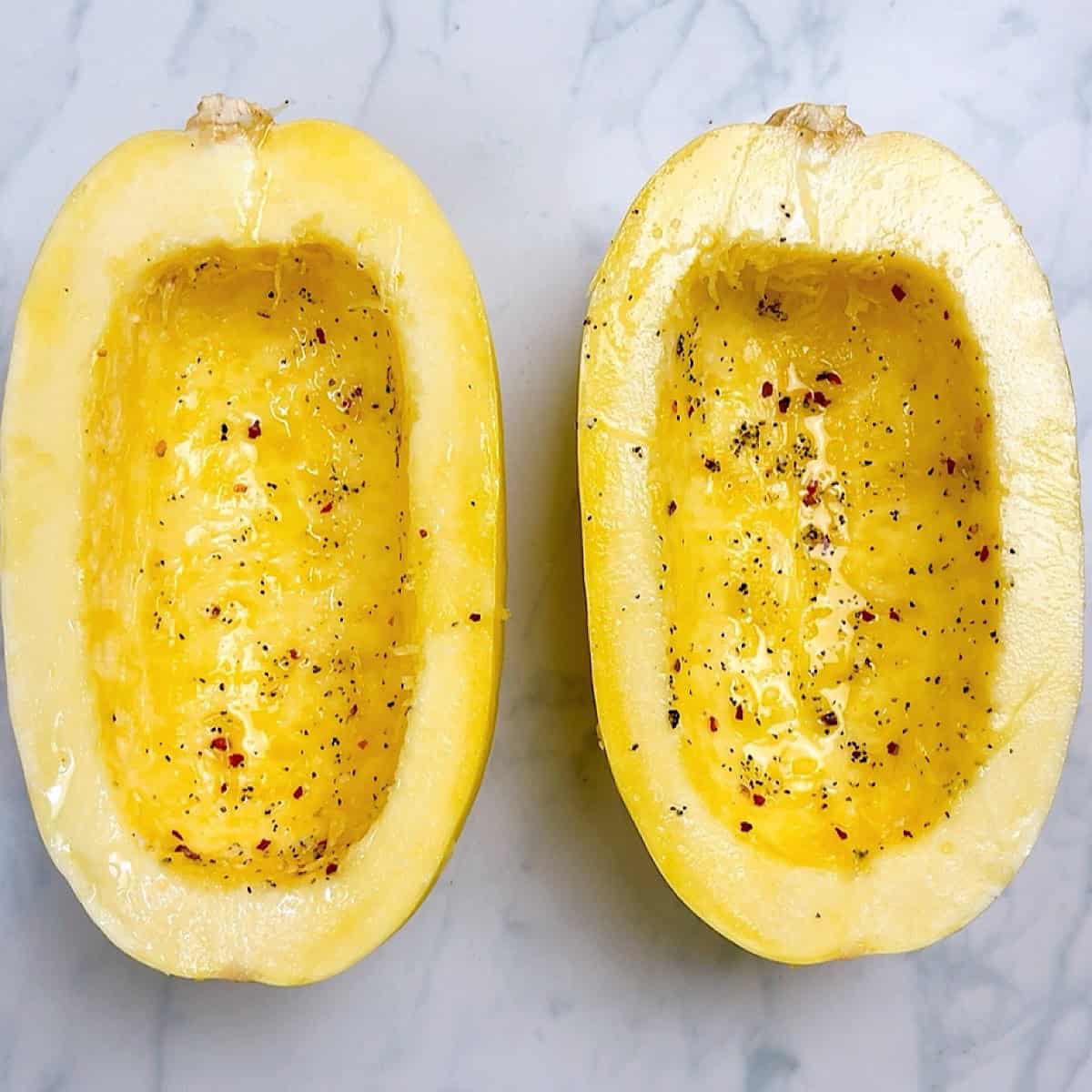 Halved spaghetti squash with oil and seasoning.