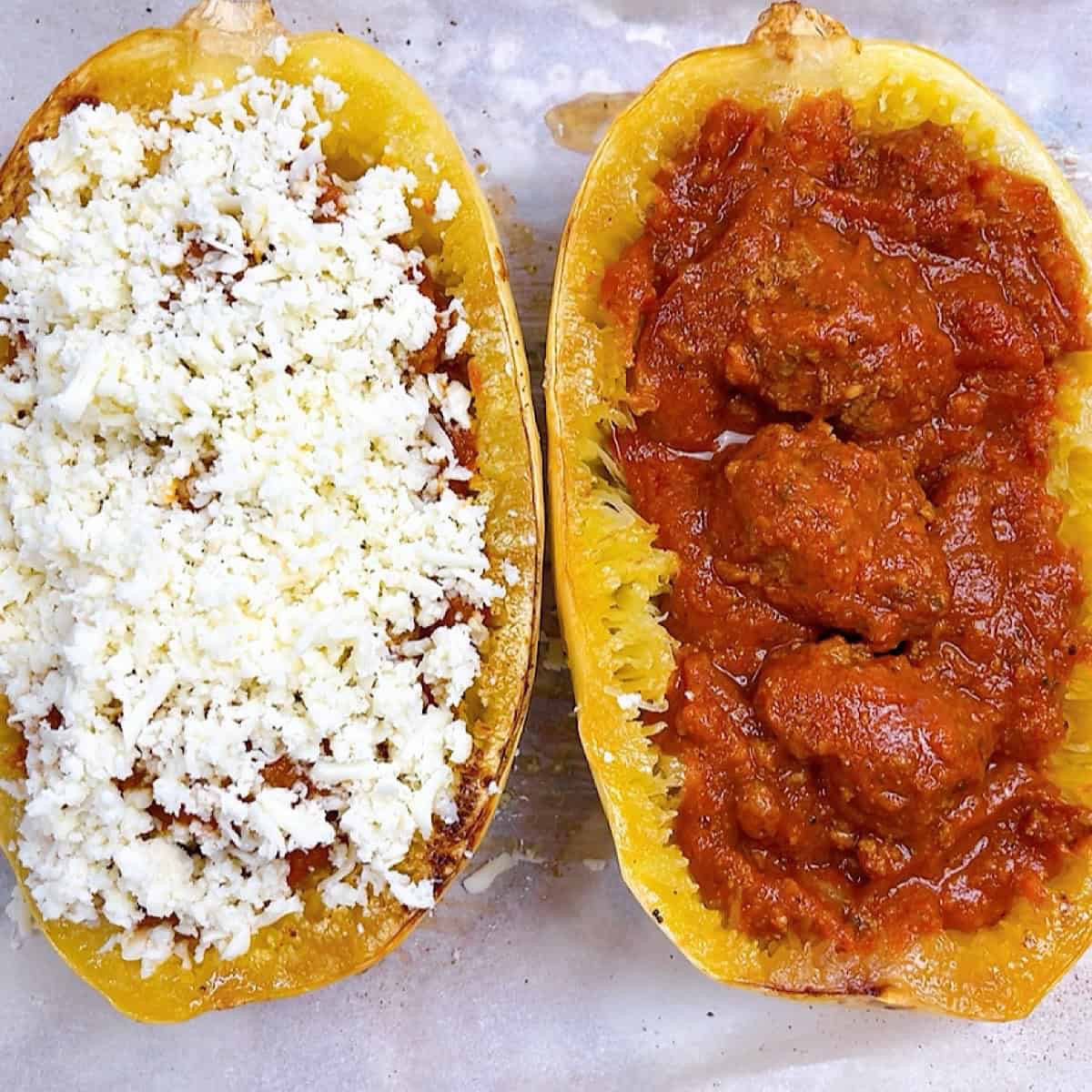 Layers of spaghetti sauce, meatballs, and cheese on each half of spaghetti squash.