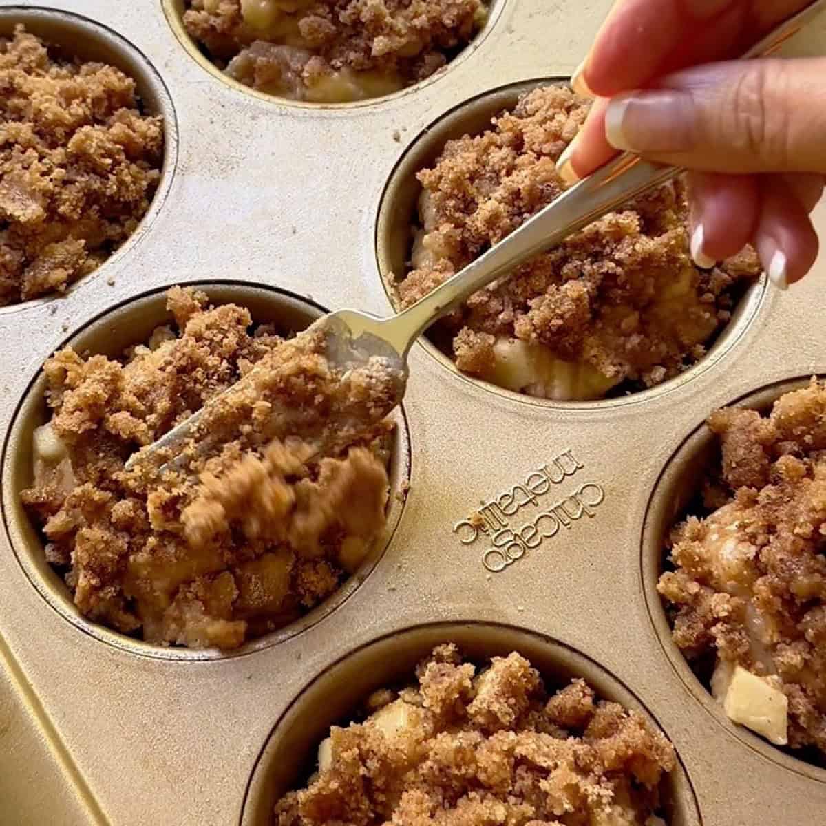 Adding streusel to the apple muffins before baking.