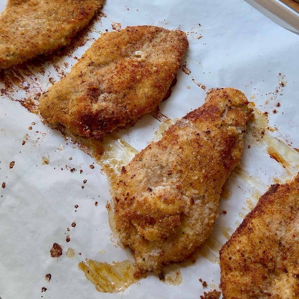 Baked crispy chicken on a sheet pan with parchment.