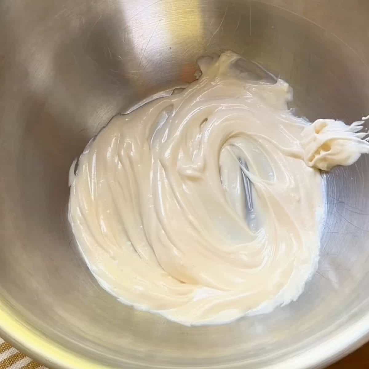 Creamy dressing whisked in bowl.