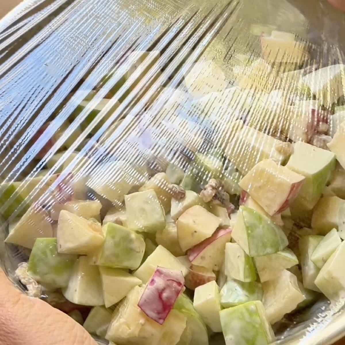 Waldorf salad covered in saran wrap and ready to chill.
