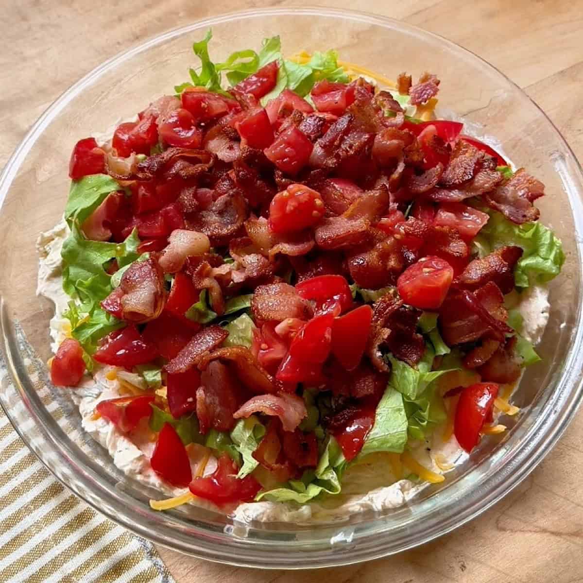 Adding bacon, lettuce, and tomato topping.