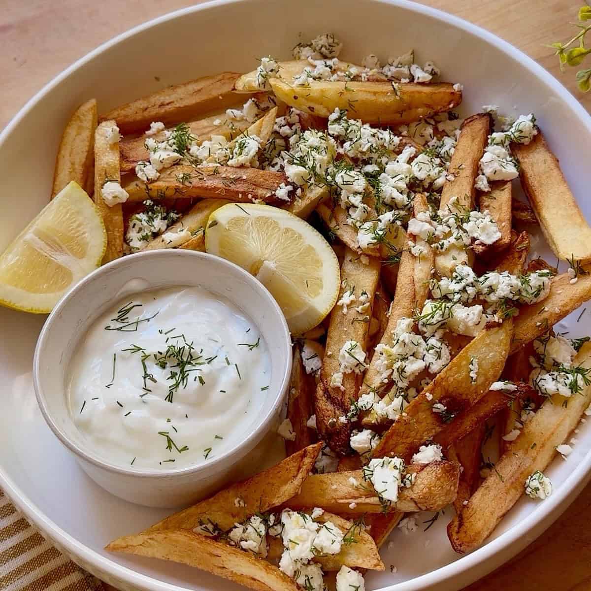 Crispy Greek feta fries in a round platter with tzatziki sauce for dipping.