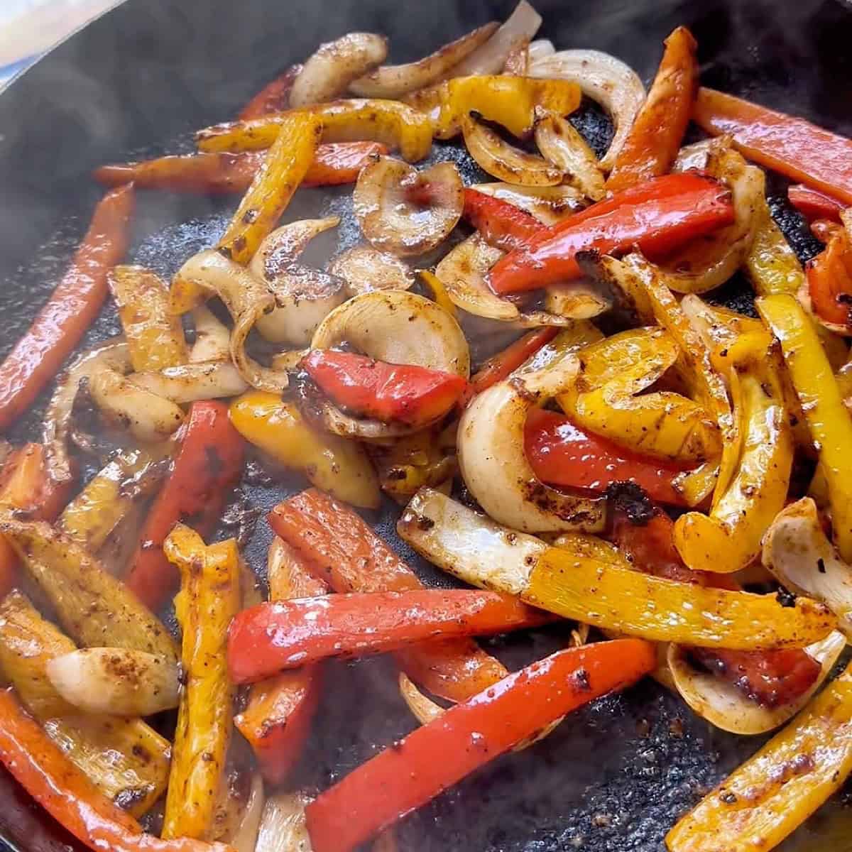 Sauteed peppers and onion with fajita seasoning in a cast iron skillet.