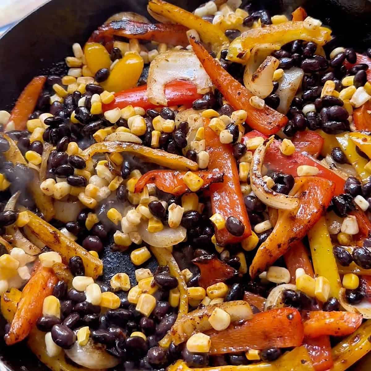 Corn and black beans added to the skillet with the peppers.