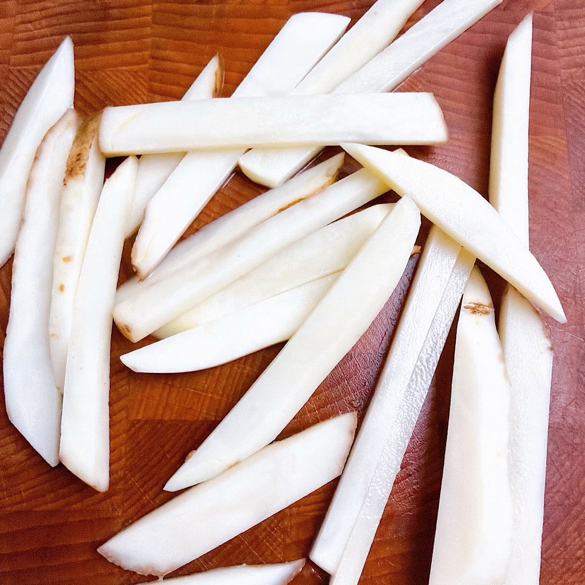 Washed and cut potatoes on a cutting board.
