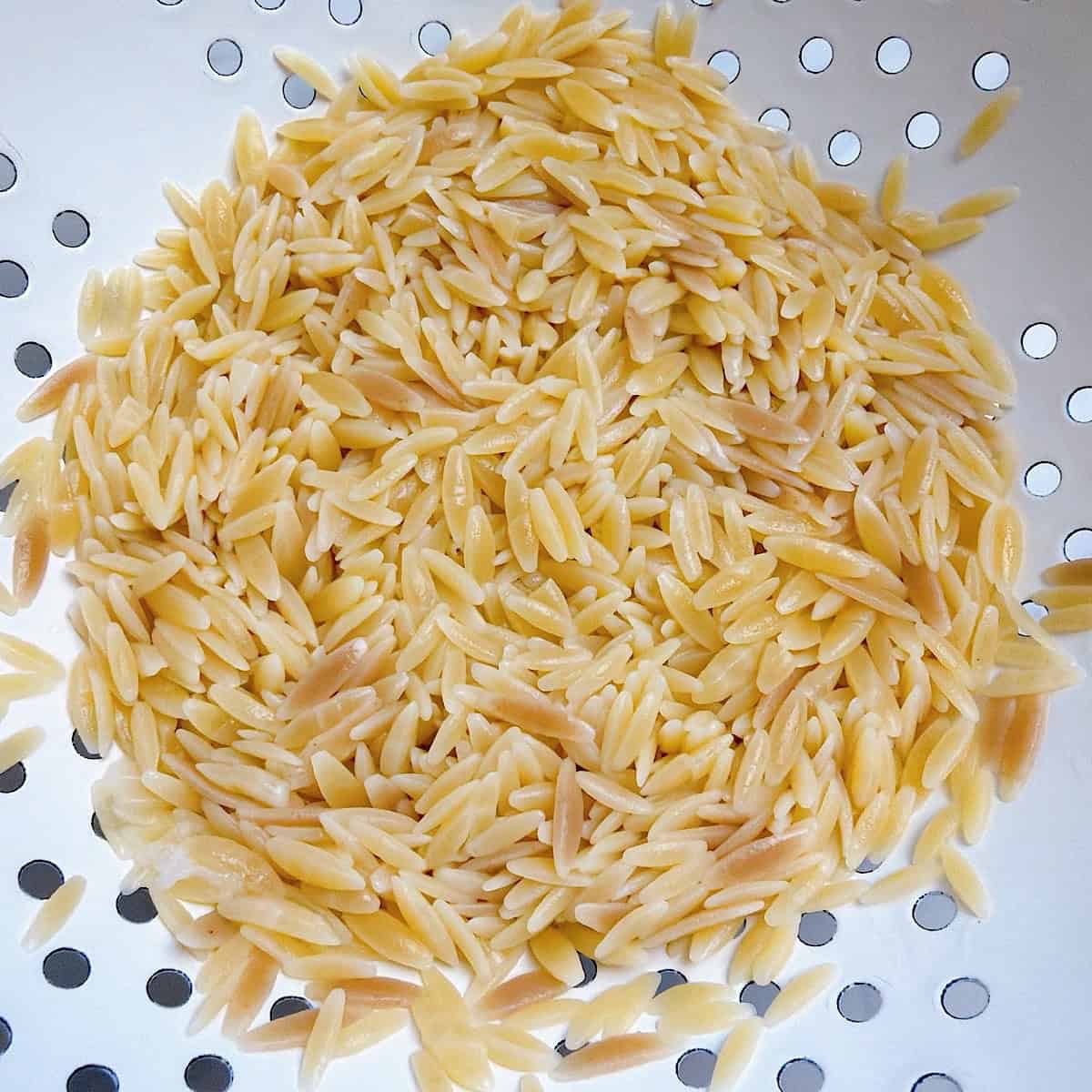 Orzo pasta draining in a colander.
