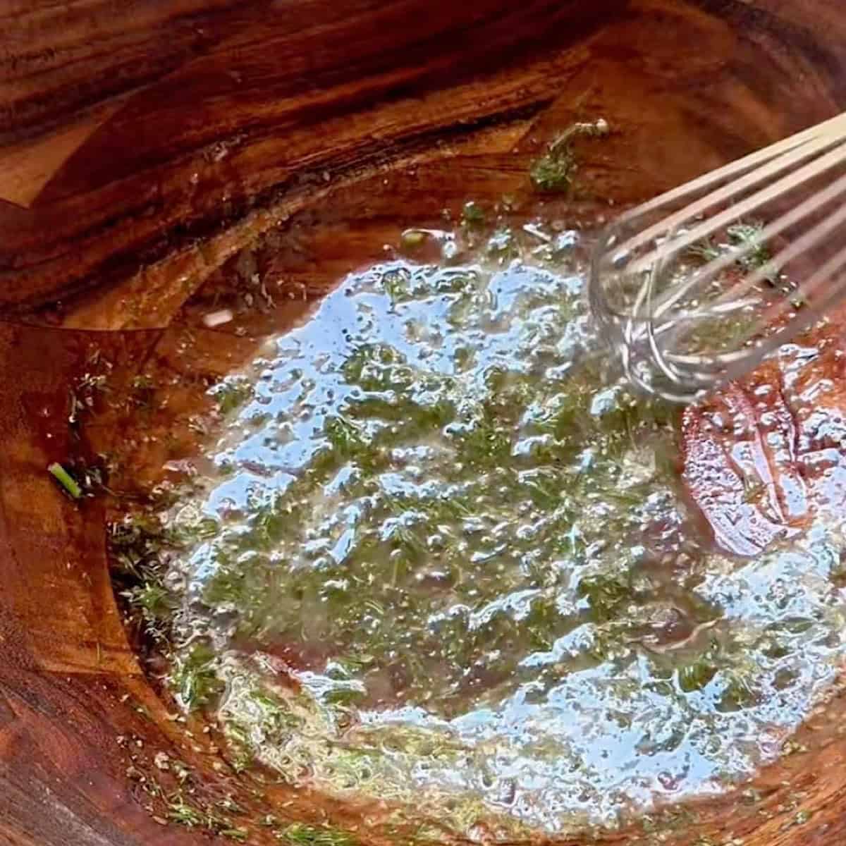 Greek dressing being whisked in a salad bowl.