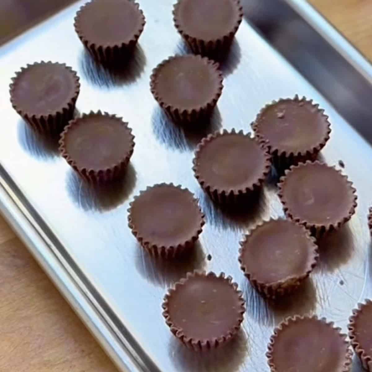 Miniature peanut butter cups unwrapped and placed on a tray for freezing.