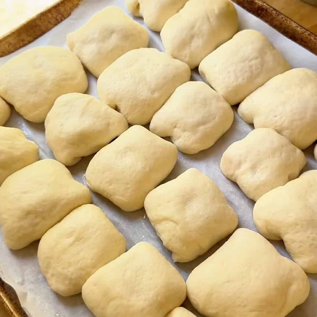 Stuffed pepperoni rolls on a sheet pan for second rise.
