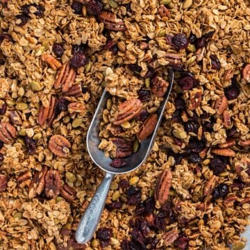 Maple pecan granola on a sheet pan with a metal scoop.