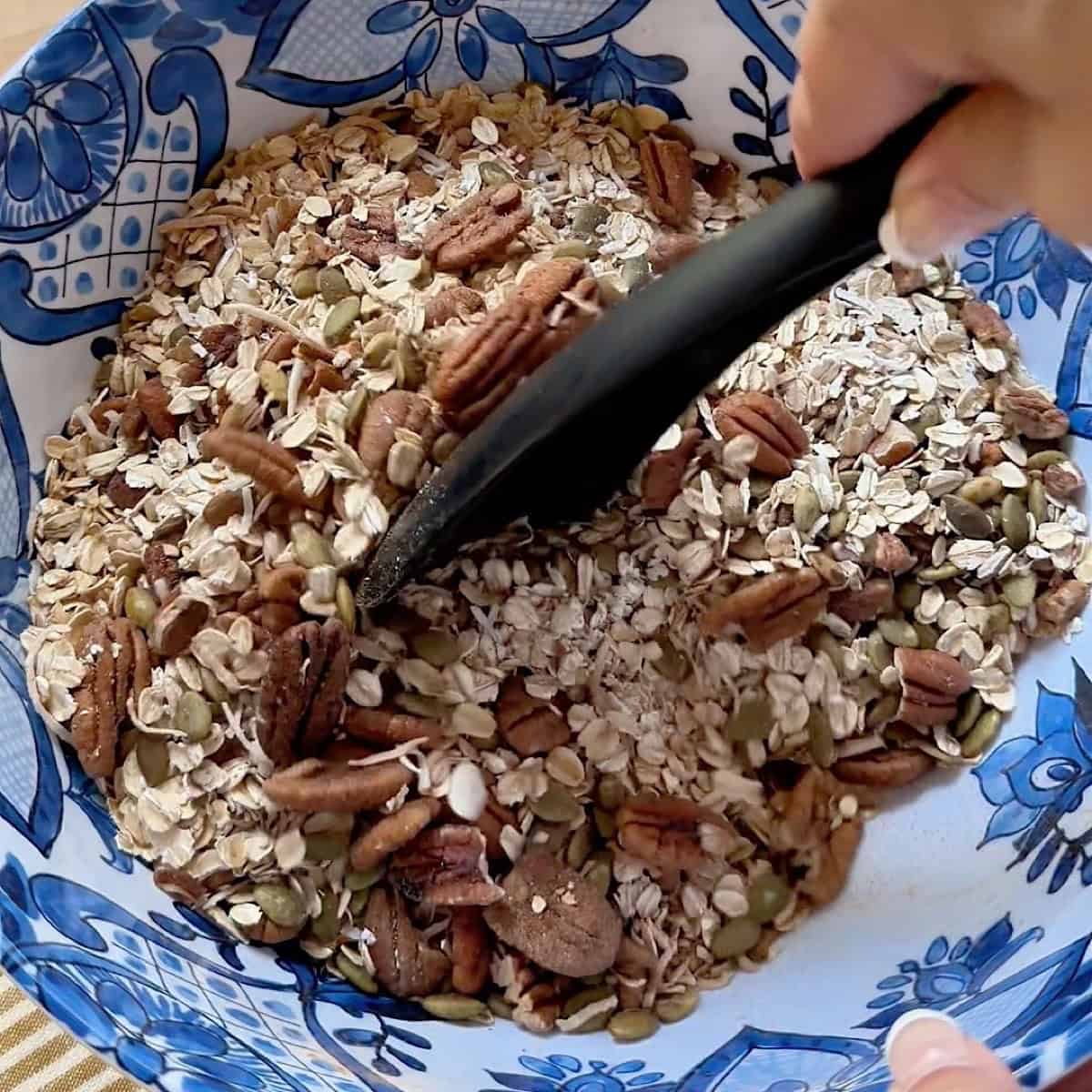Mixing maple pecan granola dry ingredients together in a large mixing bowl.
