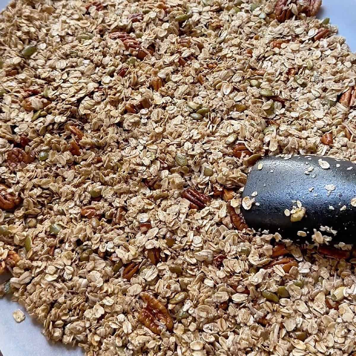 Pressing the maple granola firmly on a sheet pan.