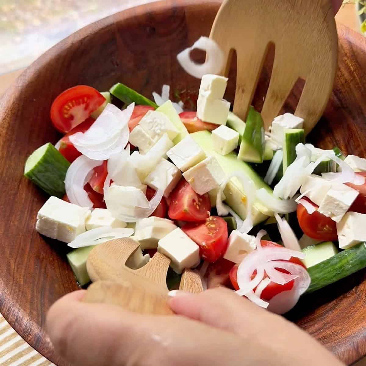 Tossing the Mediterranean salad ingredients together.