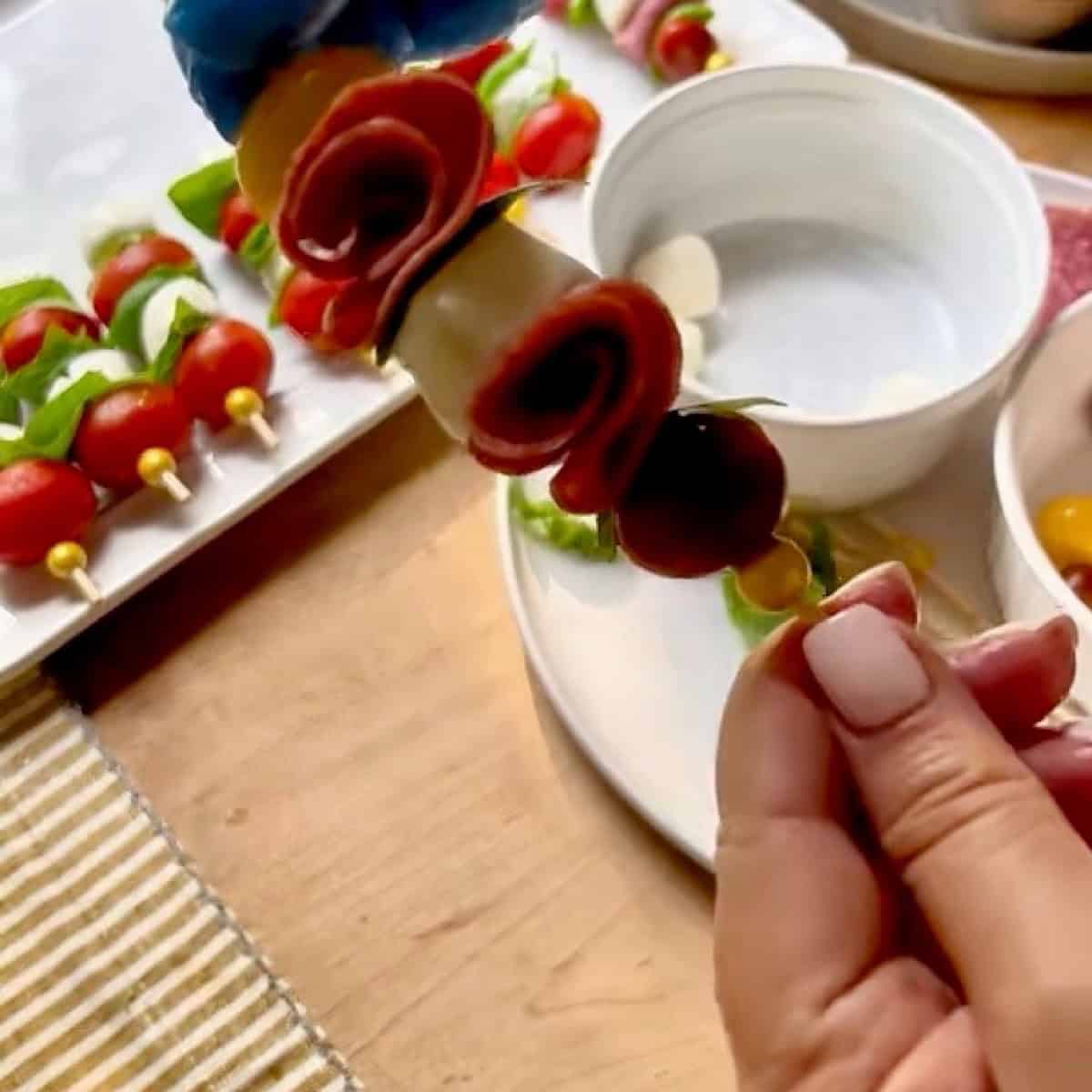 Assembling the caprese salami rose skewer.