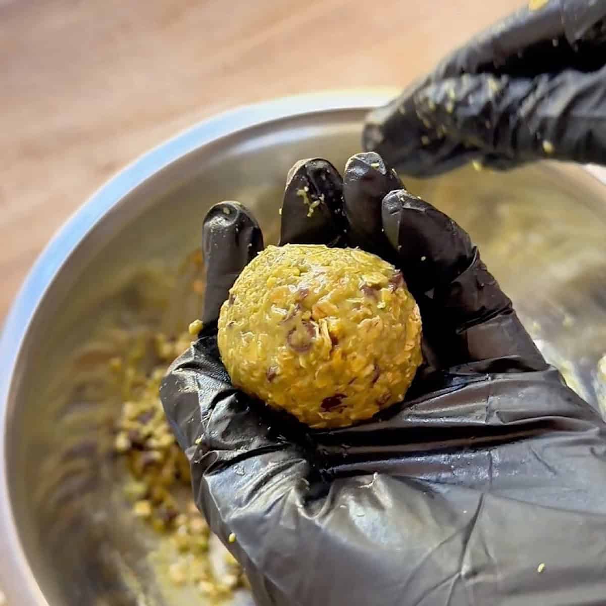 Rolling a pistachio ball into a bite sized portion.