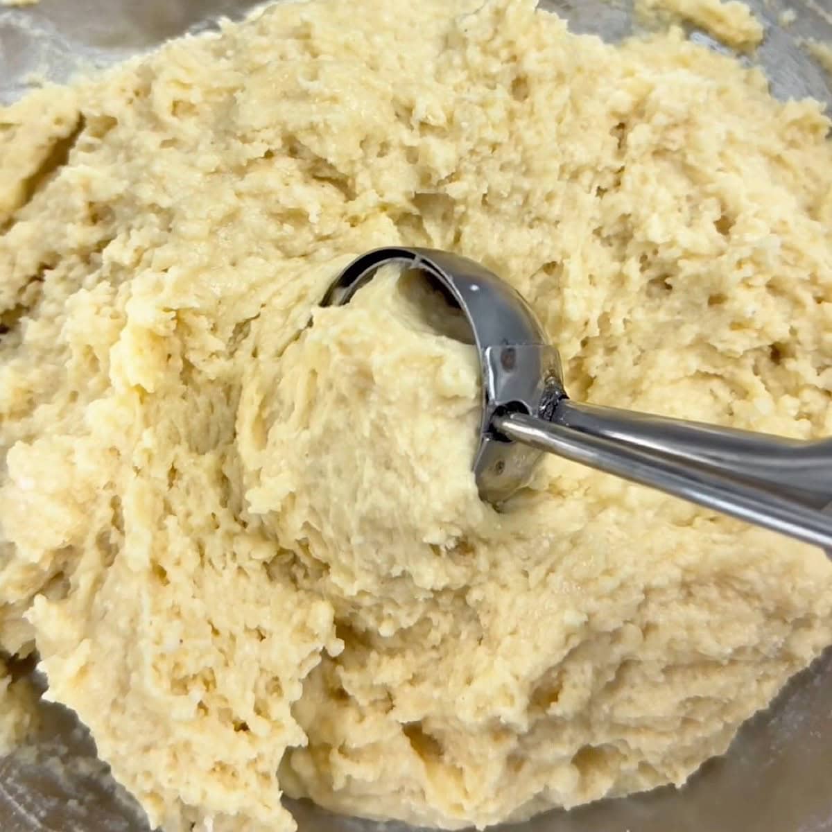 Wet and dry mixture mixed in bowl with a cookie scooper.