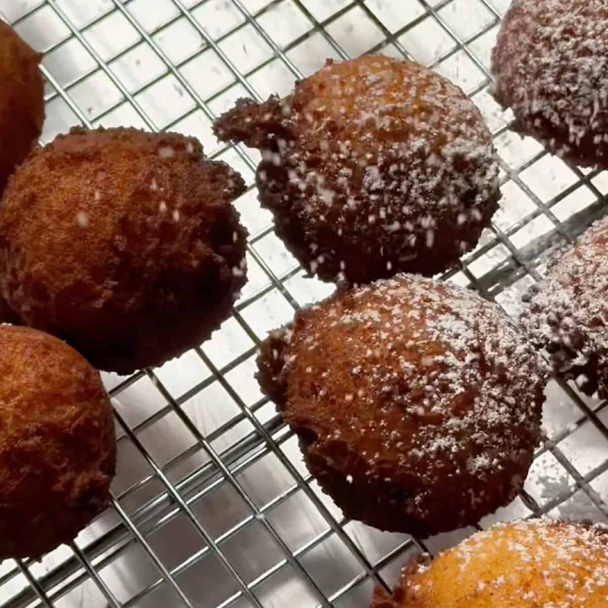 Fried zeppole being dusted with powdered sugar.