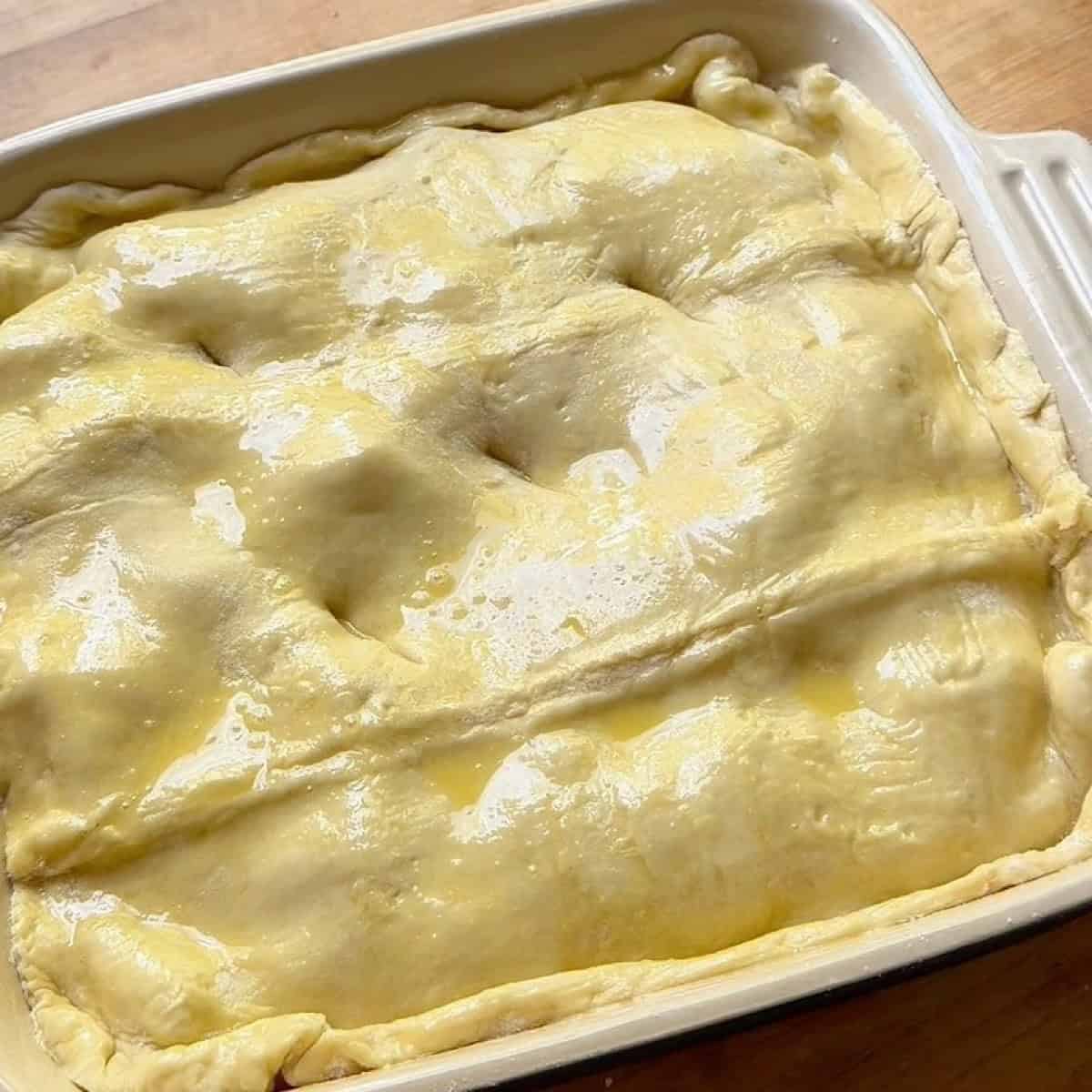 Chicken pot pie with egg washed crust pierced ready to bake.
