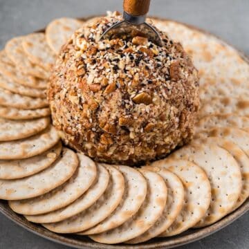 A blue cheese cheese ball on a plate surrounded by crackers.