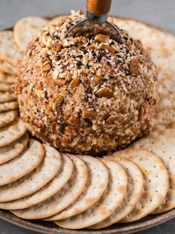 A blue cheese cheese ball on a plate surrounded by crackers.
