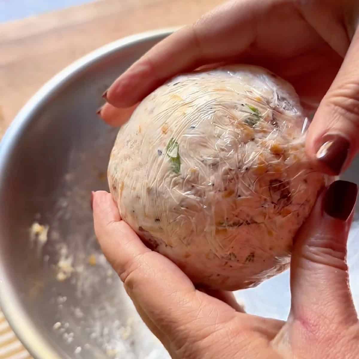 A shaped cheese ball with plastic wrap.
