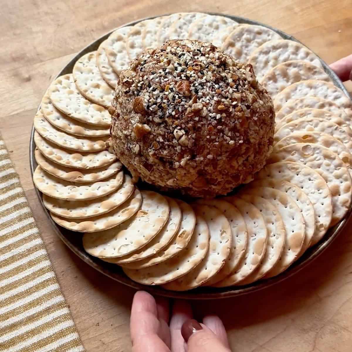 Pecan coated blue cheese and cheddar cheese ball on a serving platter with crackers.