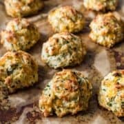 Cheddar chive drop biscuits on a sheet pan with parchment.
