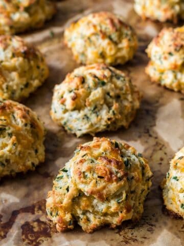 Cheddar chive drop biscuits on a sheet pan with parchment.