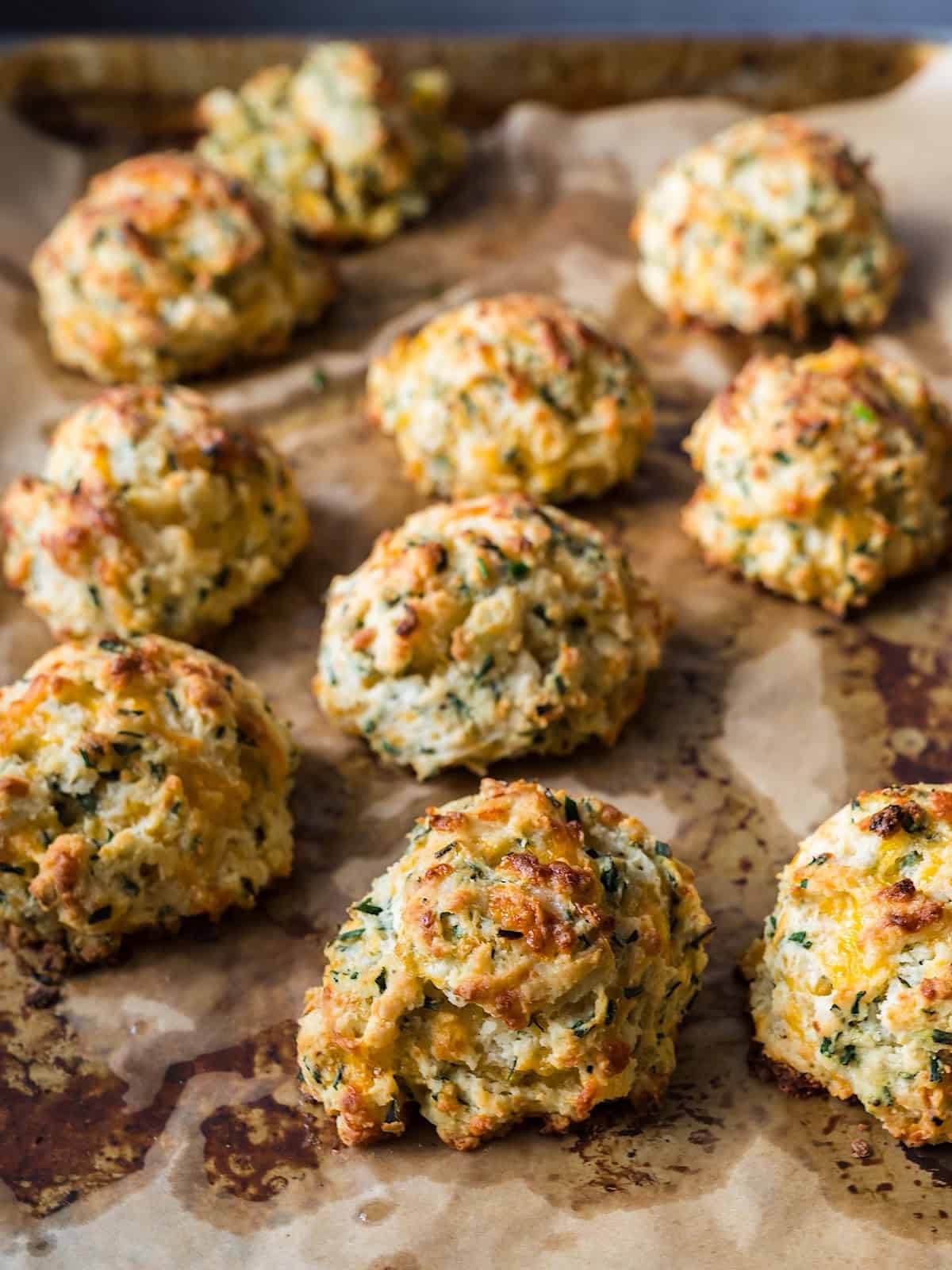 Cheddar chive drop biscuits on a sheet pan with parchment.